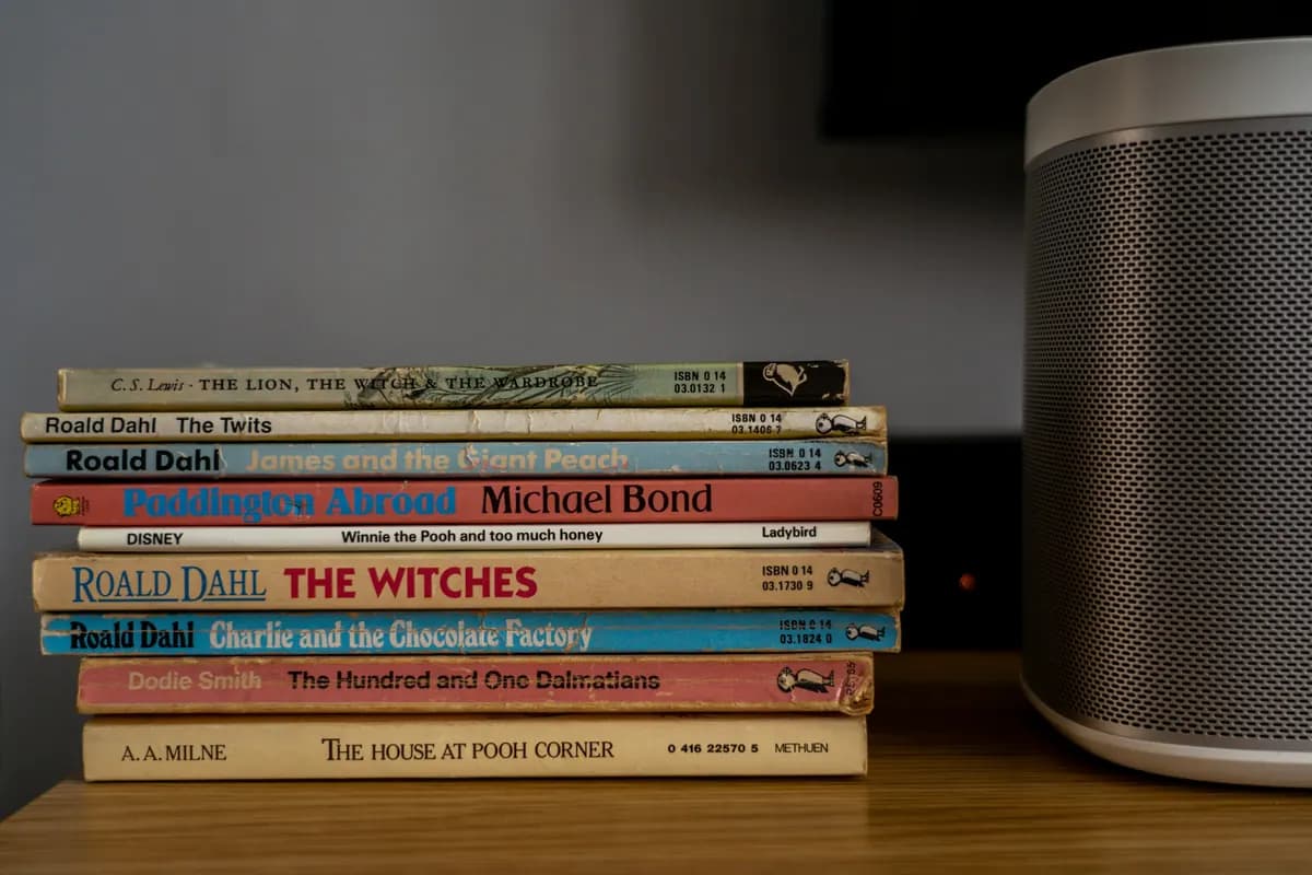 A stack of children's storybooks on a wooden shelf with the titles readable along the spines