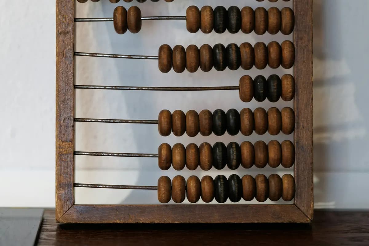 Close up of a wooden abacus with rows of brown and black beads on metal rods